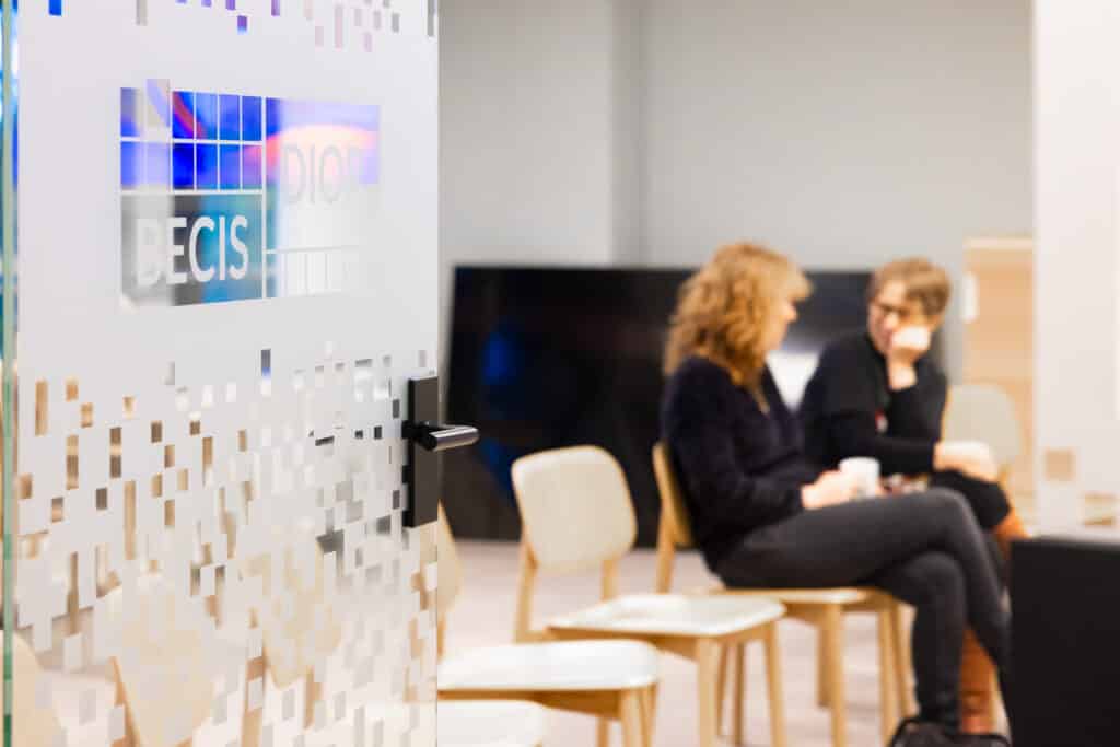 Collega's in gesprek op kantoor in trainingszaal met logo BECIS | DIOR