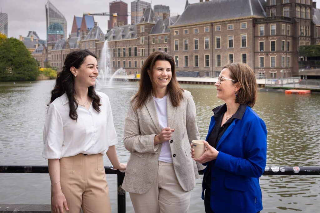 Collega's lachen met elkaar, op de achtergrond de Hofvijver Den Haag